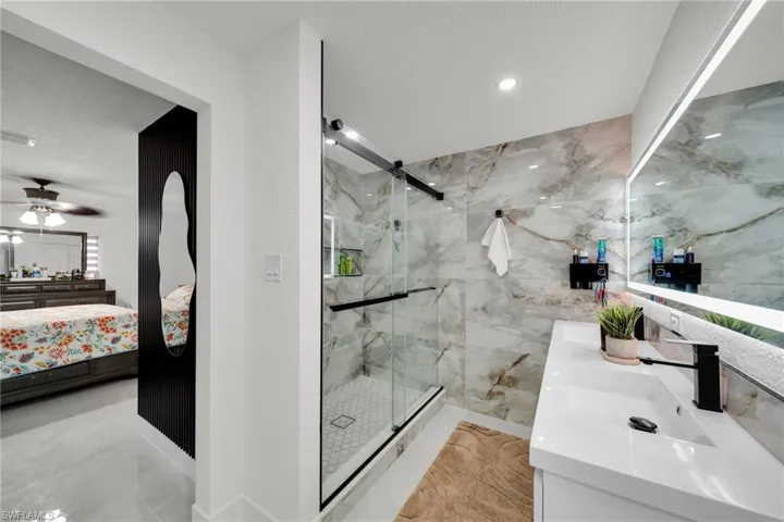 Contemporary bathroom with a glass-enclosed shower featuring a patterned tile floor and stone-look wall tiling