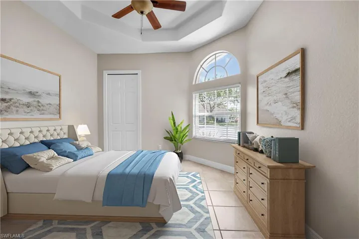 Tiled bedroom with a closet, ceiling fan, and a raised ceiling