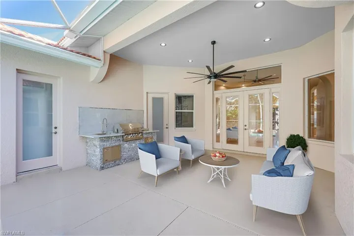 View of patio featuring grilling area, ceiling fan, an outdoor kitchen, sink, and french doors
