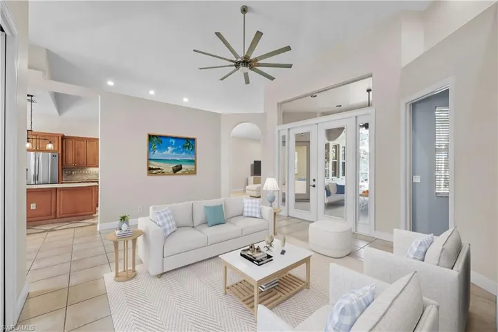 Tiled living room with high vaulted ceiling, french doors, and ceiling fan