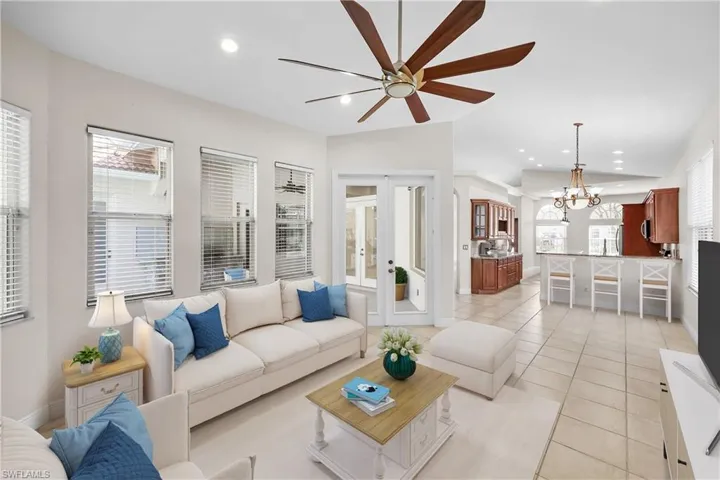 Living room featuring light tile flooring and ceiling fan with notable chandelier