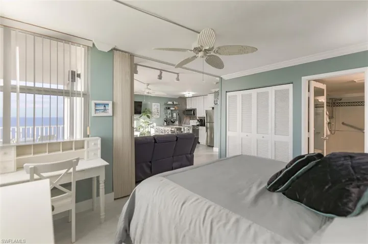 Bedroom featuring ceiling fan, fridge, a closet, track lighting, and crown molding