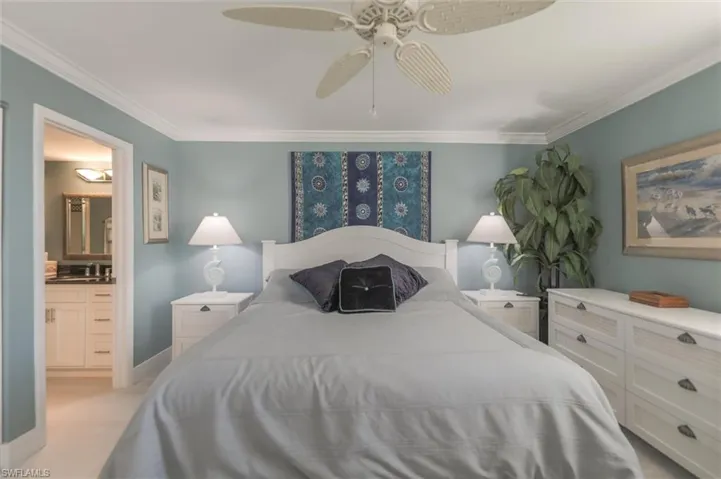 Carpeted bedroom with sink, ceiling fan, crown molding, and ensuite bath
