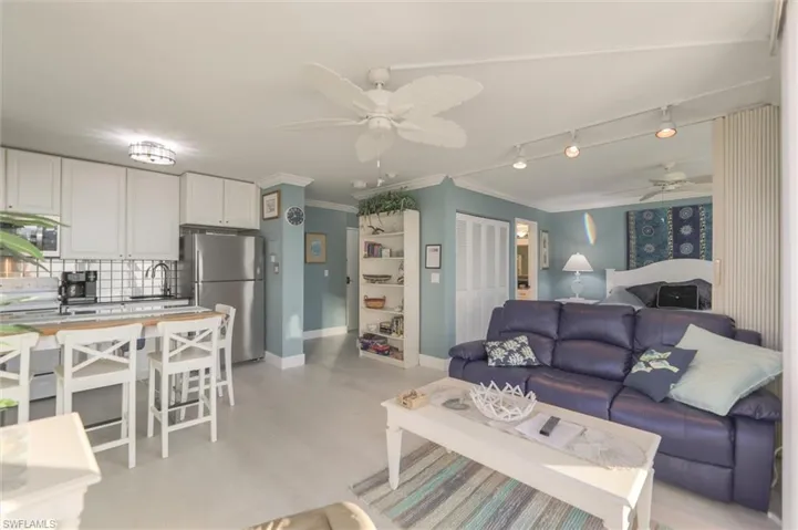 Living room with ceiling fan, rail lighting, sink, and ornamental molding