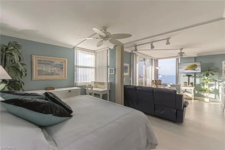 Bedroom with ceiling fan, light wood-type flooring, track lighting, and ornamental molding