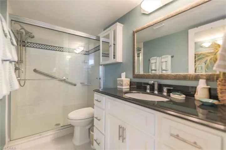 Bathroom with toilet, vanity, walk in shower, and tile patterned floors