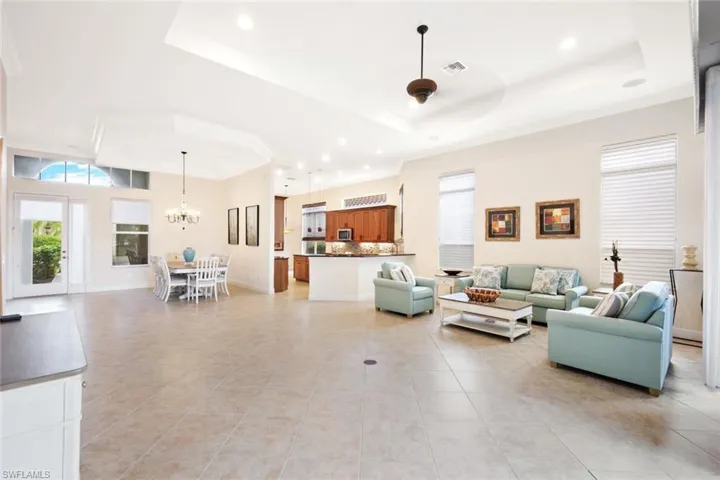 Living area featuring recessed lighting, a raised ceiling, light tile patterned floors, and a chandelier