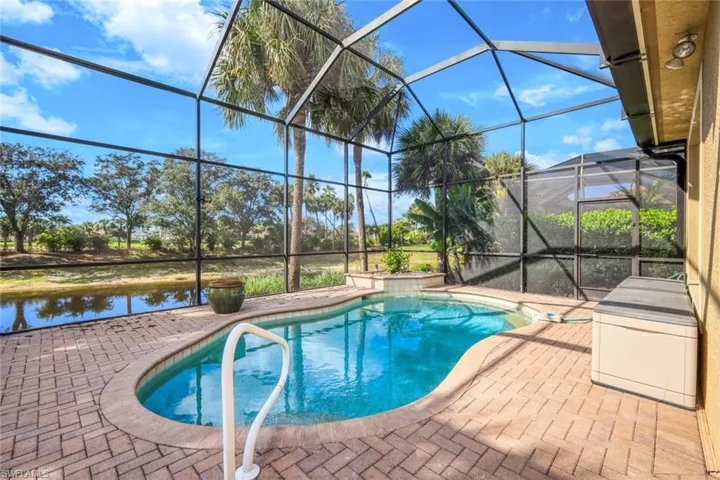Outdoor pool with a sunroom, a patio, glass enclosure, and a water view