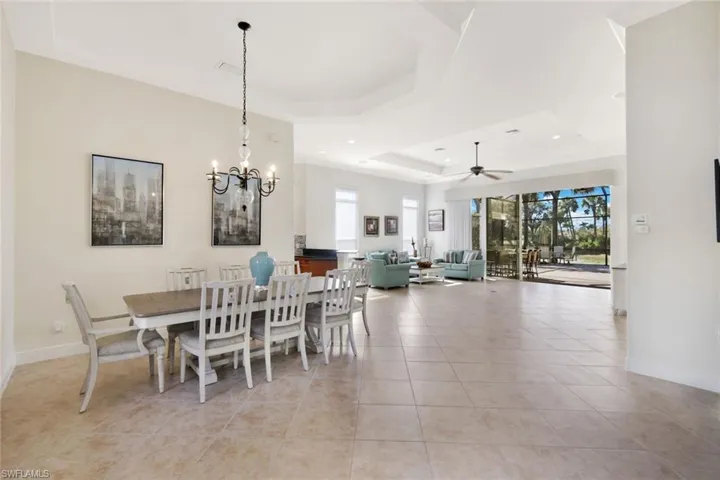 Dining area featuring a tray ceiling, light tile patterned flooring, a chandelier, ceiling fan, and recessed lighting