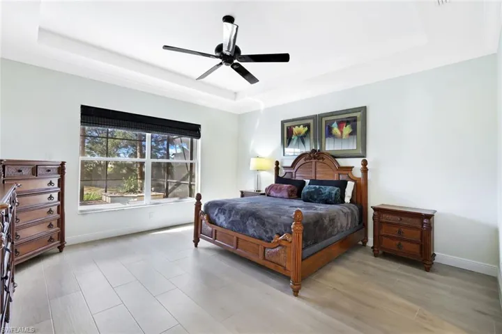 Bedroom featuring a raised ceiling, wood tiled floors, and a ceiling fan