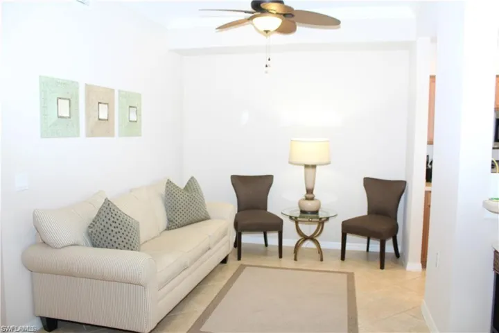 Living room with baseboards, light tile patterned floors, crown molding, and a ceiling fan