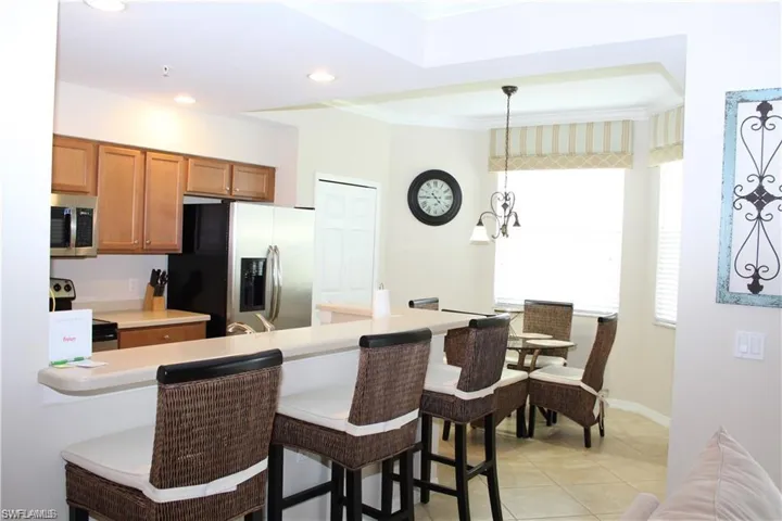 Kitchen featuring a breakfast bar area, appliances with stainless steel finishes, crown molding, and brown cabinets