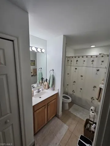 Full bath with vanity, light tile patterned floors, and shower / bath combo