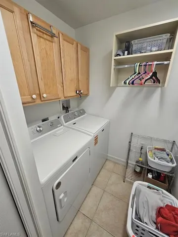 Laundry room with washer and clothes dryer, light tile patterned floors, and cabinet space