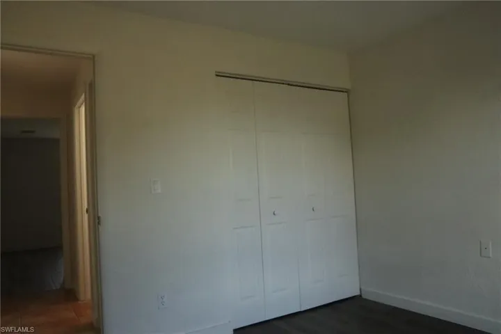 Unfurnished bedroom with a closet and dark wood-type flooring
