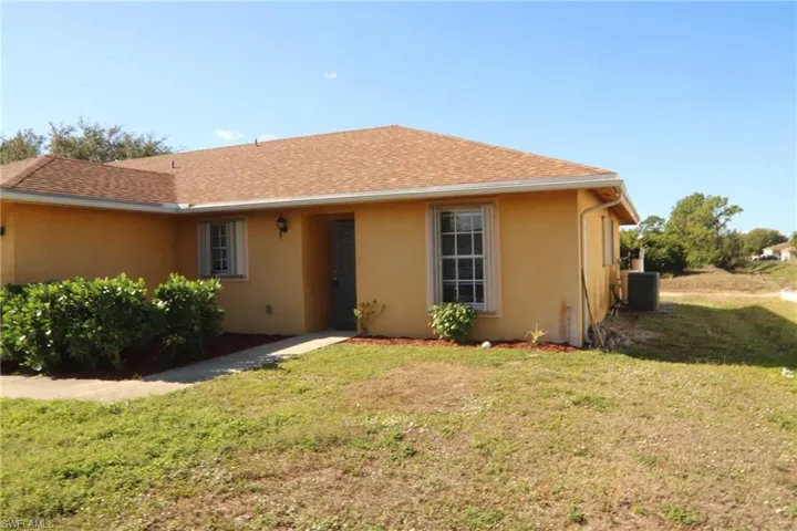 Single story home with a front lawn, stucco siding, and roof with shingles