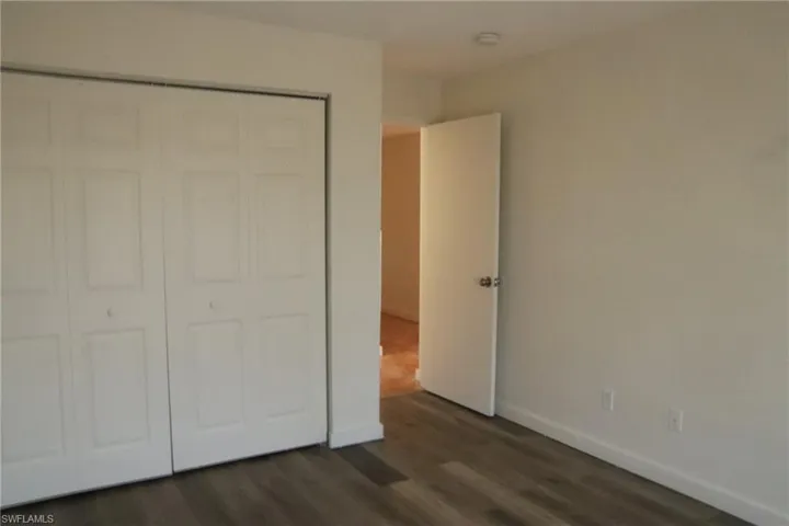 Unfurnished bedroom with a closet and dark wood-type flooring