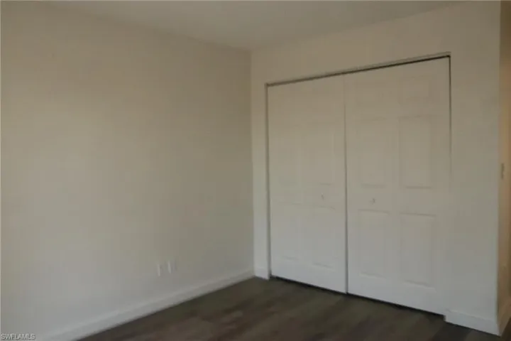Unfurnished bedroom featuring dark wood finished floors and a closet