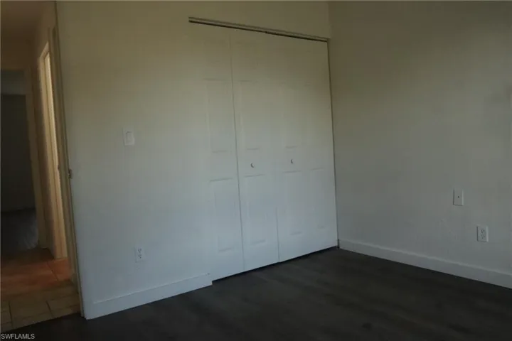 Unfurnished bedroom with a closet and dark wood-style floors