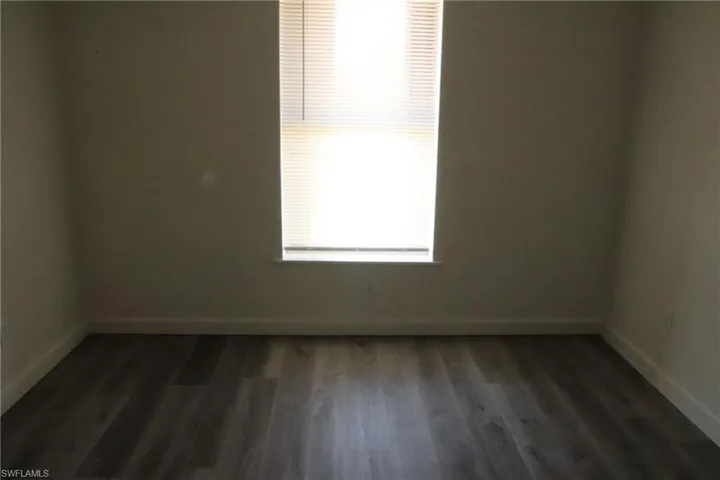 Empty room featuring dark wood finished floors and baseboards