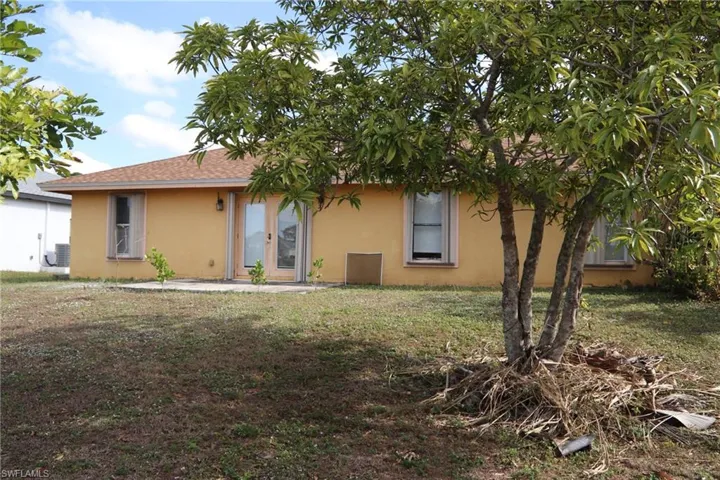 Rear view of property featuring stucco siding, a yard, a patio area, and a shingled roof