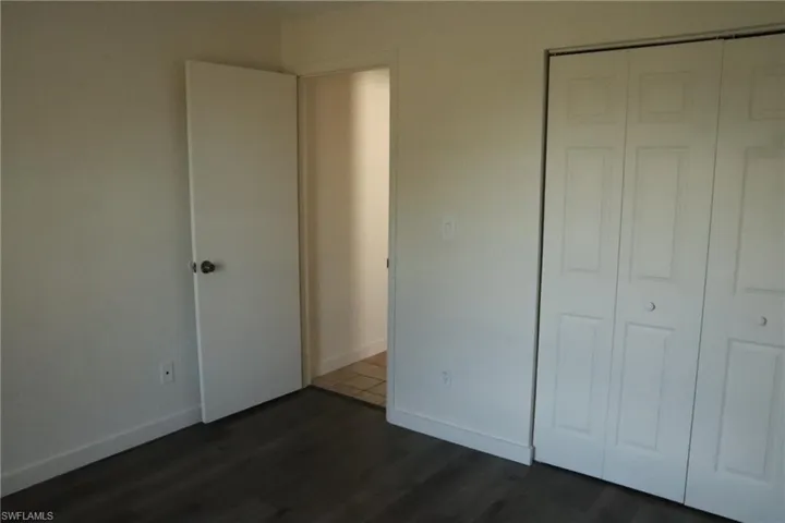 Unfurnished bedroom featuring dark wood-style flooring and a closet