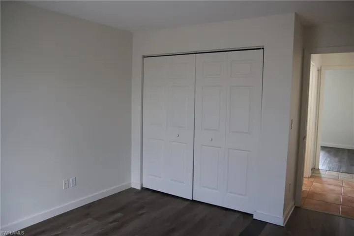 Unfurnished bedroom featuring dark wood-style floors and a closet