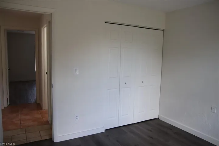 Unfurnished bedroom featuring dark wood-style floors and a closet