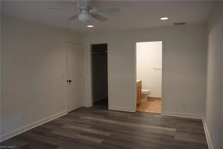 Unfurnished bedroom with a ceiling fan, dark wood-style floors, recessed lighting, and connected bathroom