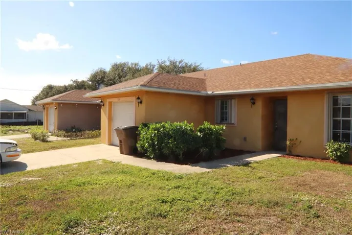 Ranch-style home with stucco siding, an attached garage, concrete driveway, and a front yard