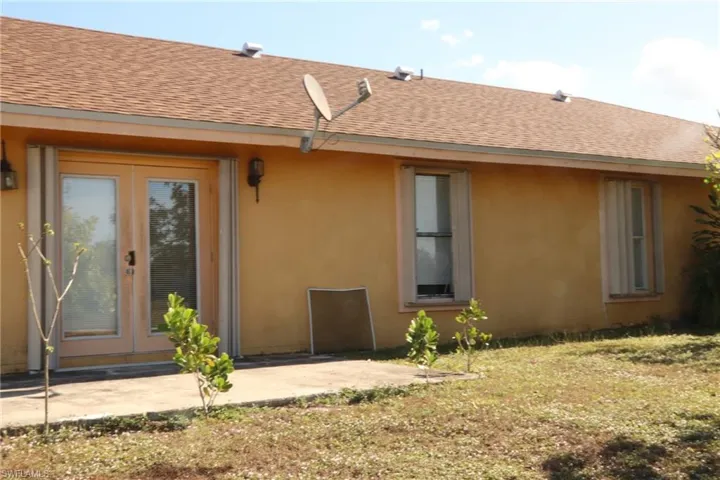 Rear view of property with a patio area, stucco siding, roof with shingles, and french doors