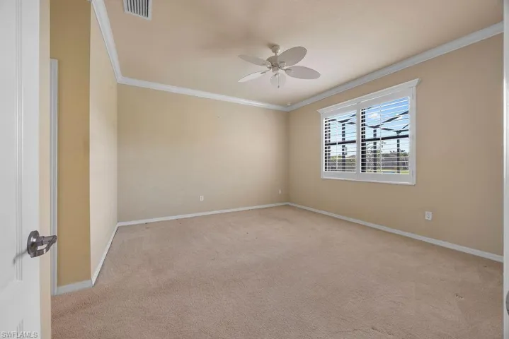 Primary bedroom with baseboards, a ceiling fan, visible vents, and crown molding