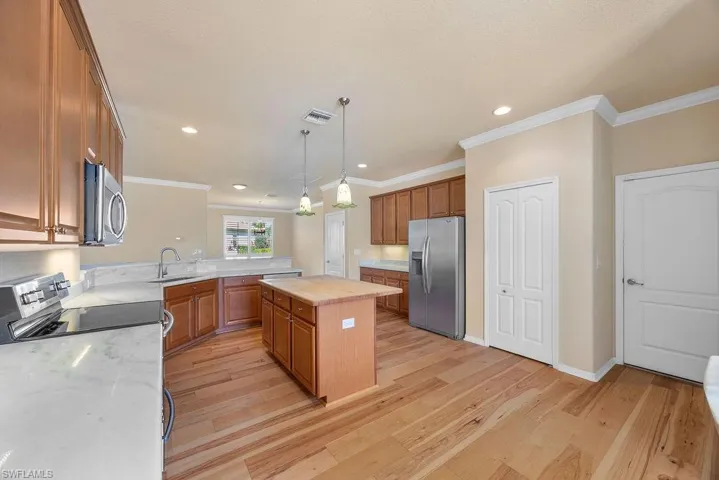 Kitchen featuring brown cabinetry, appliances with stainless steel finishes, a sink, and visible vents