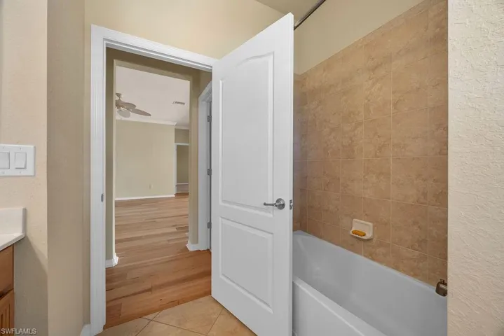 Bathroom featuring tile patterned floors, baseboards, crown molding, vanity, and shower / tub combination