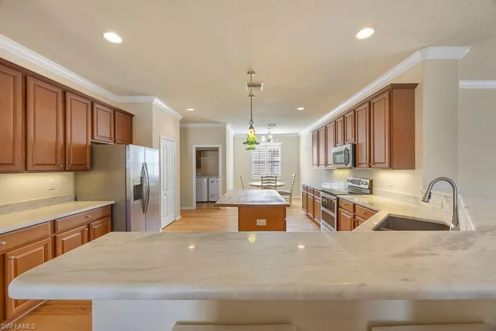 Kitchen featuring a sink, separate washer and dryer, crown molding, a kitchen island, and appliances with stainless steel finishes