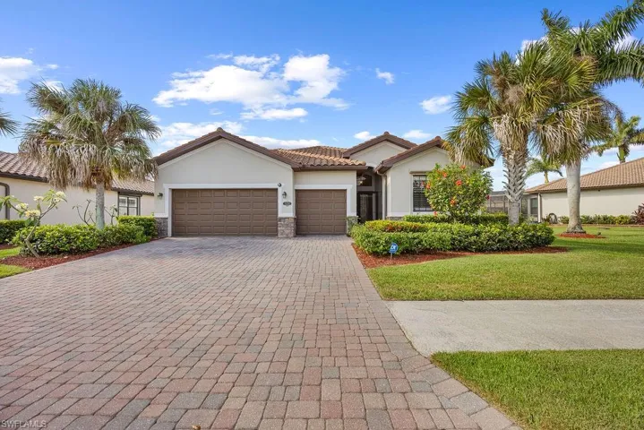 Home featuring decorative driveway, stone siding, an attached garage, a front yard, and stucco siding