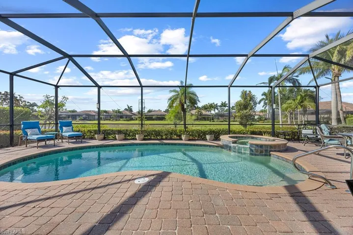 View of swimming pool with screened enclosure, a connected hot tub, and a patio area