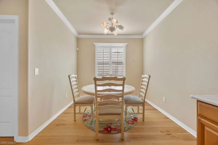 Dining space featuring baseboards, light wood-style floors, a chandelier, and ornamental molding