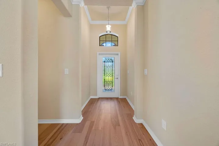 Entryway featuring light wood finished floors, crown molding, and baseboards