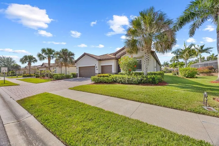 View of front of home featuring a tiled roof, an attached garage, a front yard, stucco siding, and decorative driveway