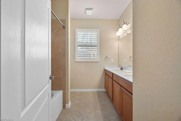 Full bath featuring a sink, shower / bathing tub combination, double vanity, tile patterned flooring, and visible vents