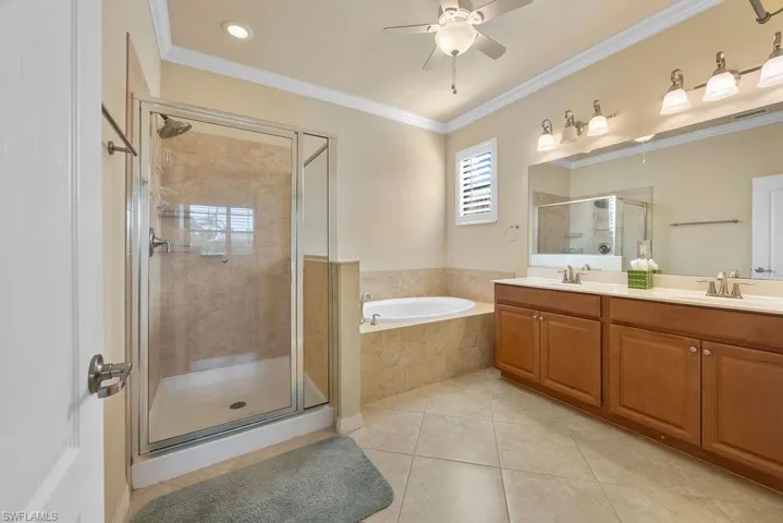 Primary Bathroom featuring a garden tub, a ceiling fan, a sink, a stall shower, and tile flooring