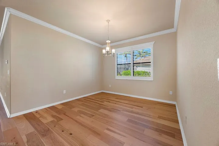 Dining room featuring a chandelier, baseboards, light wood-style floors, and ornamental molding