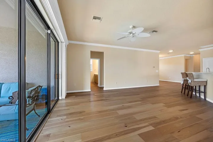 Living room featuring visible vents, a ceiling fan, baseboards, and ornamental molding