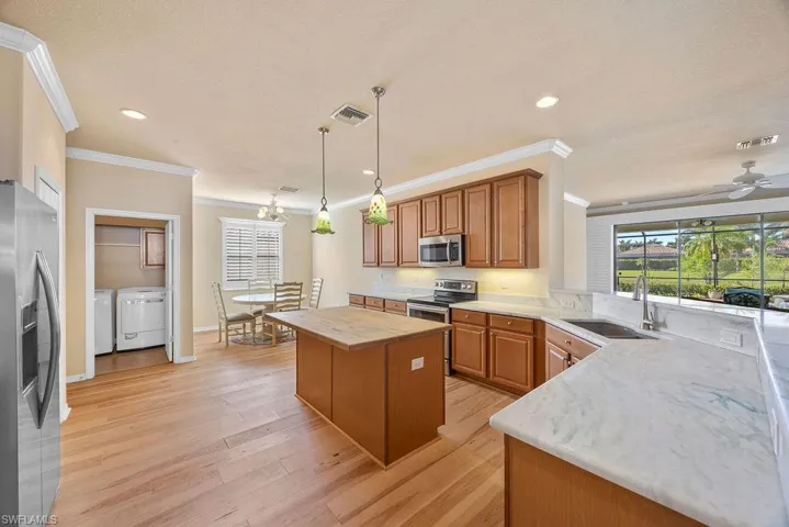 Kitchen featuring visible vents, ornamental molding, a sink, washing machine and dryer, and appliances with stainless steel finishes