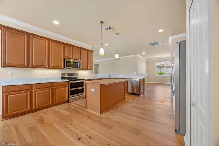 Kitchen featuring a peninsula, visible vents, crown molding, light countertops, and appliances with stainless steel finishes