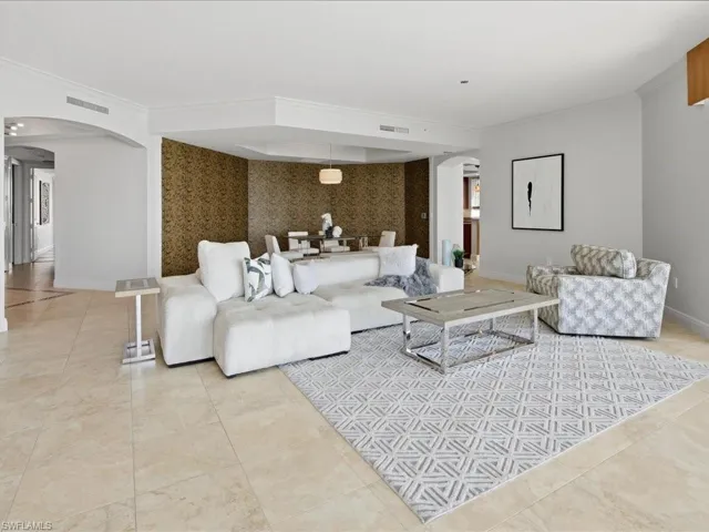 Open-concept living space featuring high ceilings, crown molding, and large format tile flooring