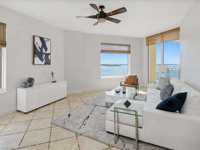 Expansive living area featuring large windows with water scenery, diagonally laid tile flooring, a modern ceiling fan, and a built-in console cabinet