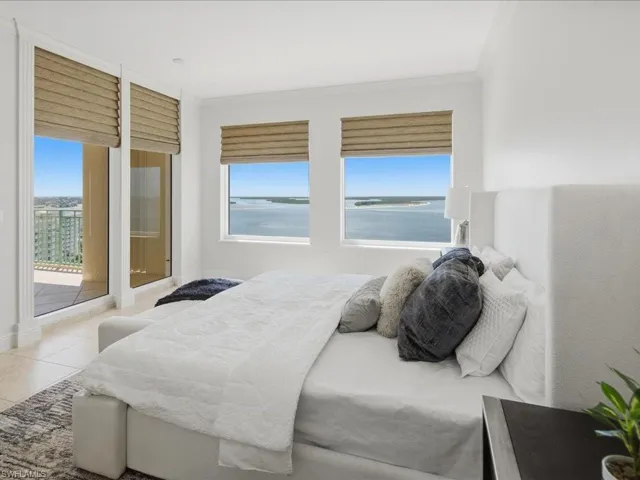 Room featuring multiple windows and a glass door with custom window treatments, offering water and distant land scenery