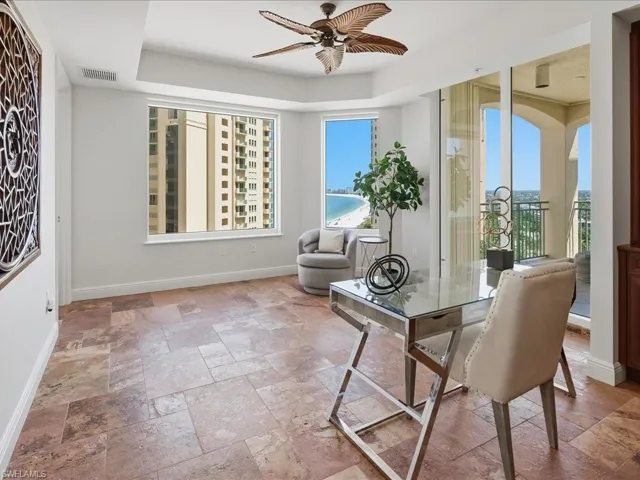 Spacious room featuring large format tile flooring, a window providing beach and water views, and direct access to a private balcony